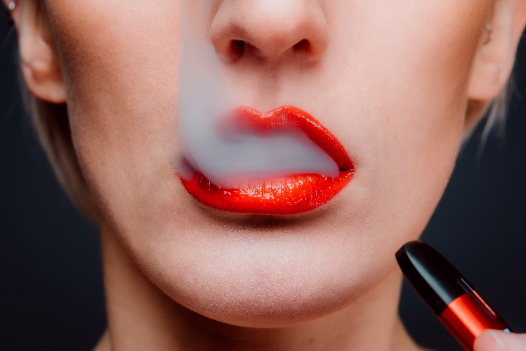 Close-up of a person exhaling vapour while holding a vape